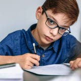 Teen writing in his notebook at school.