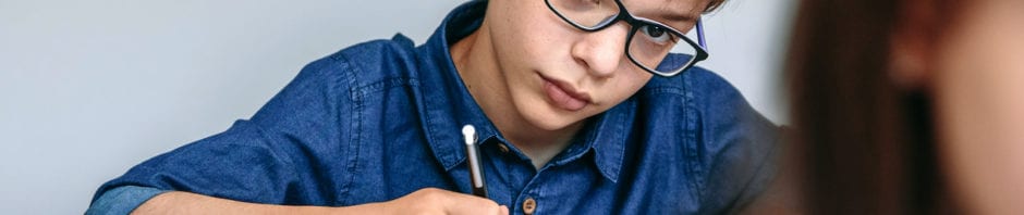 Teen writing in his notebook at school.