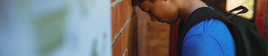 Child in crisis - sad schoolboy leaning on brick wall