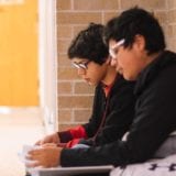 Two Latinx boys sitting in a school hallway together