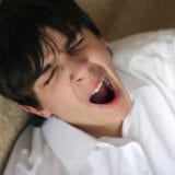 About Sleep - Teen yawning while leaning back on sofa