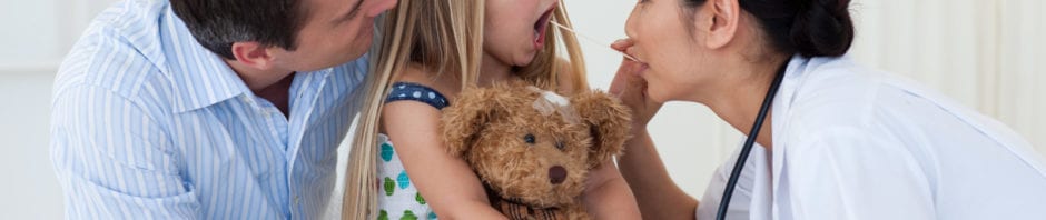 Doctor examining child's throat during a check-up, with parent in the room