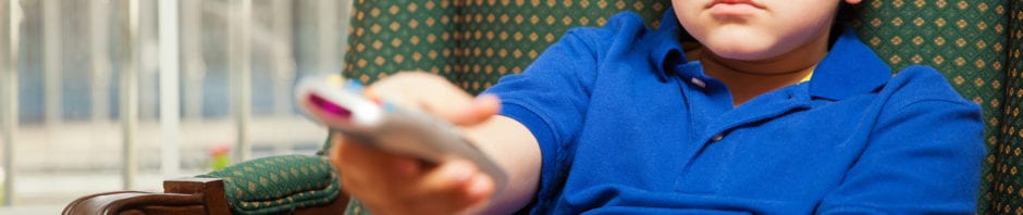 Young male child sitting leaning back on sofa flipping through channels