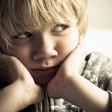 Specific Phobias - Young boy leaning his cheeks on his hands looking worried